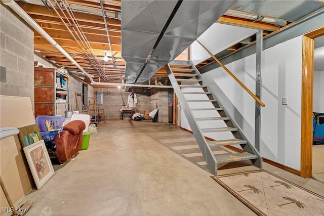 unfinished basement with concrete block wall and stairway