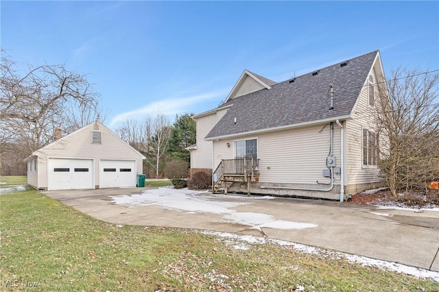 view of side of property featuring a garage, an outbuilding, roof with shingles, and a yard