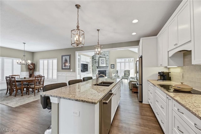 kitchen featuring an island with sink, a breakfast bar area, stainless steel appliances, white cabinetry, and a sink