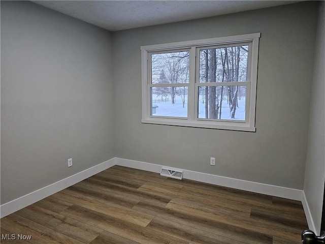 spare room featuring visible vents, baseboards, and wood finished floors