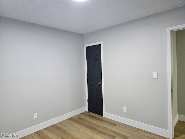 empty room with baseboards and light wood-style floors