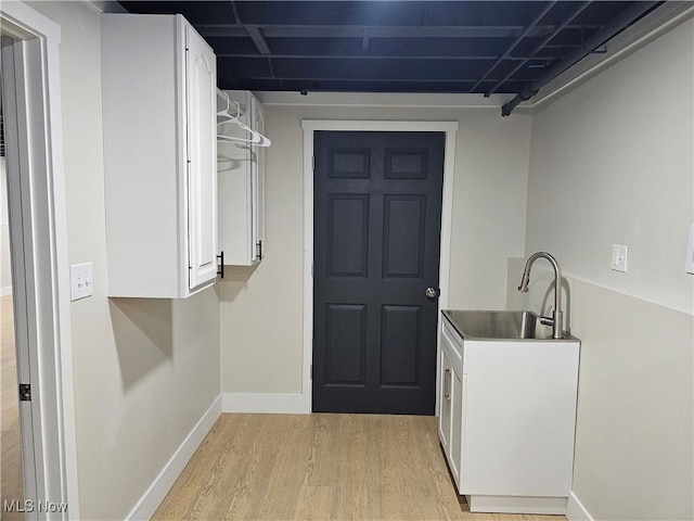 interior space featuring light wood finished floors, baseboards, and a sink