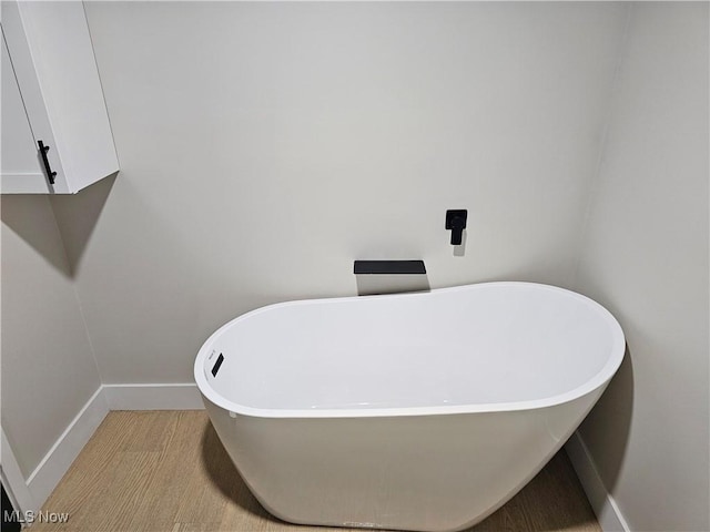 bathroom with a freestanding bath and baseboards