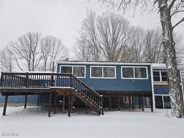 snow covered property featuring a deck and stairs