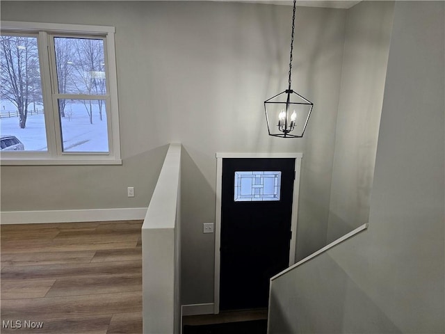 entryway featuring an inviting chandelier, stairway, baseboards, and wood finished floors