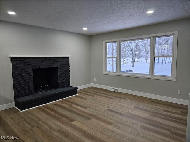 unfurnished living room featuring a healthy amount of sunlight, baseboards, visible vents, and wood finished floors