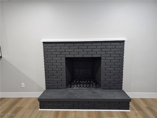 interior details featuring a fireplace, wood finished floors, and baseboards