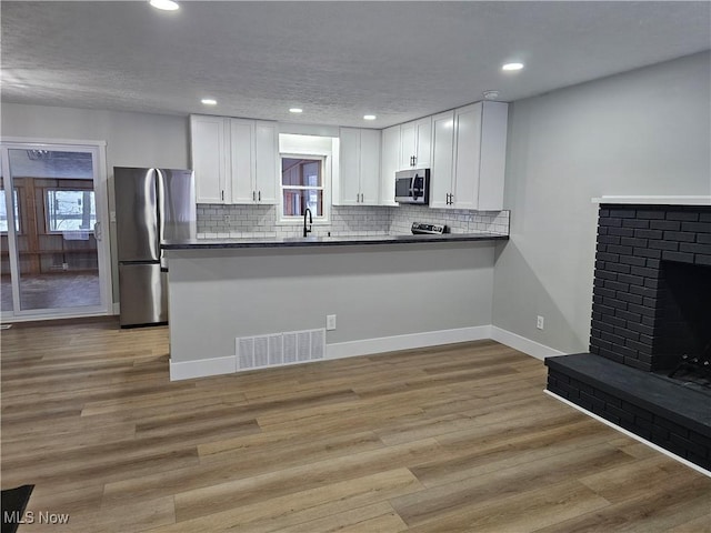 kitchen with appliances with stainless steel finishes, white cabinetry, visible vents, and a peninsula