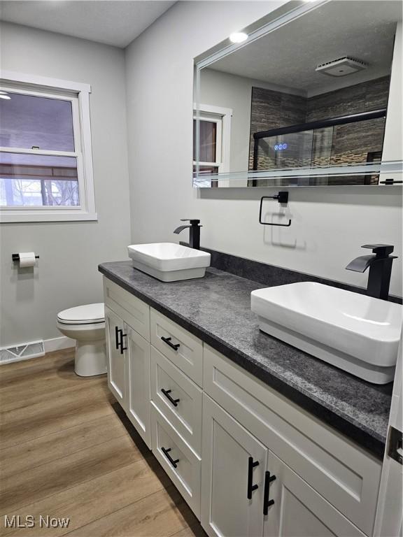 bathroom featuring a stall shower, visible vents, a sink, and wood finished floors