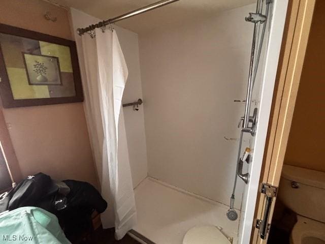 bathroom featuring toilet and a shower stall