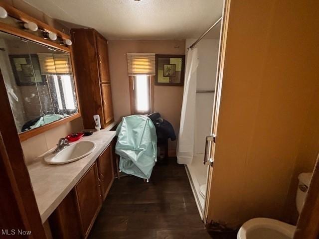 full bathroom featuring a shower stall, a textured ceiling, and vanity