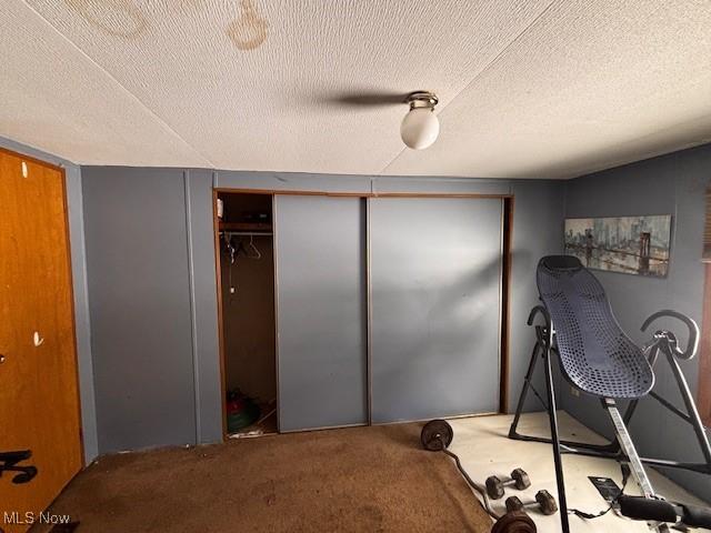 carpeted bedroom featuring a ceiling fan and a textured ceiling