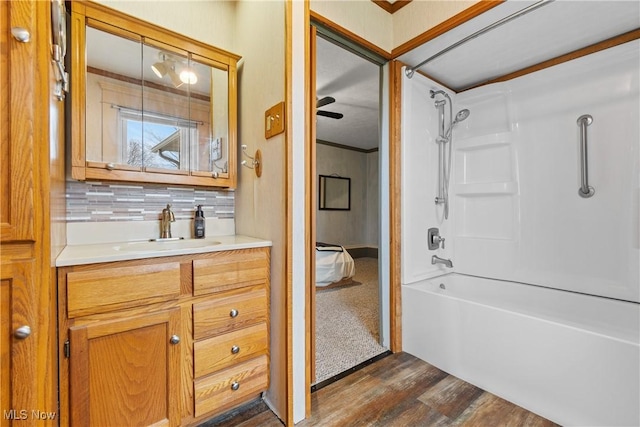 bathroom with tub / shower combination, vanity, decorative backsplash, and wood finished floors