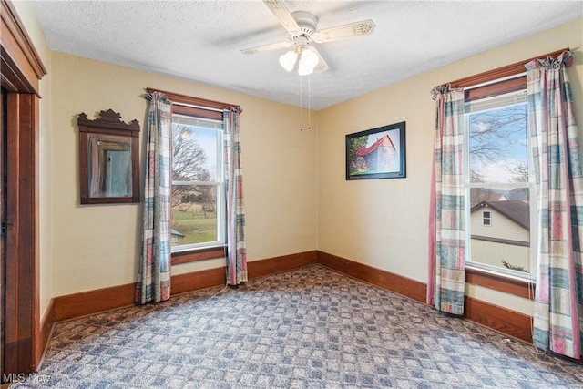 spare room with a textured ceiling, a ceiling fan, and baseboards