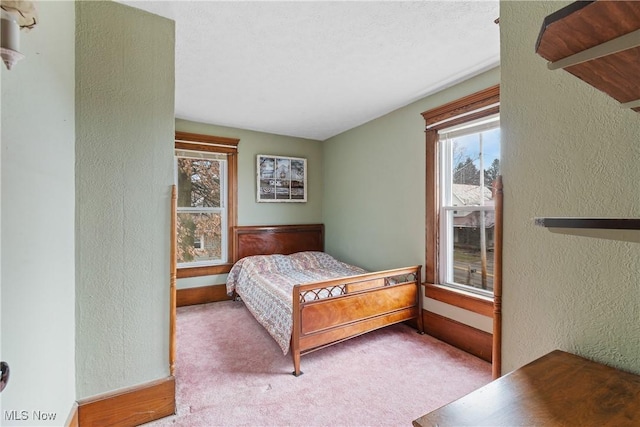 carpeted bedroom featuring multiple windows, a textured ceiling, and a textured wall