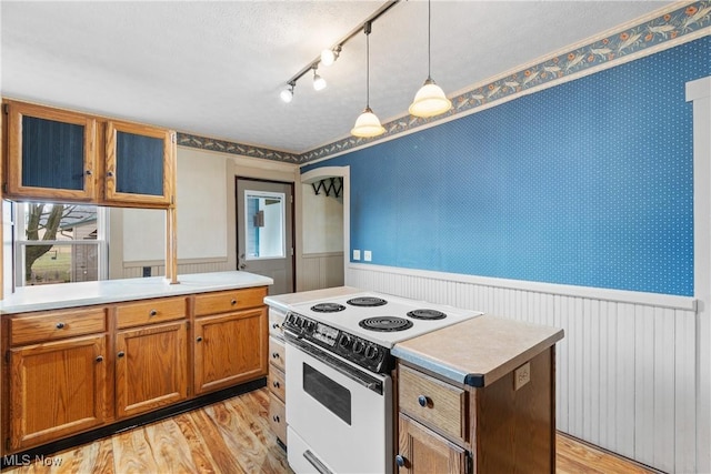 kitchen featuring electric range, pendant lighting, light countertops, and wainscoting