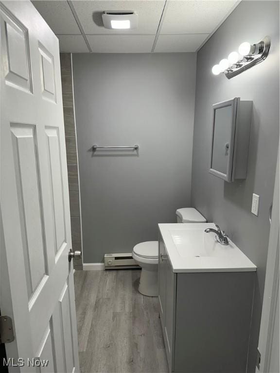 spare room with a paneled ceiling, light wood-style flooring, baseboards, and baseboard heating