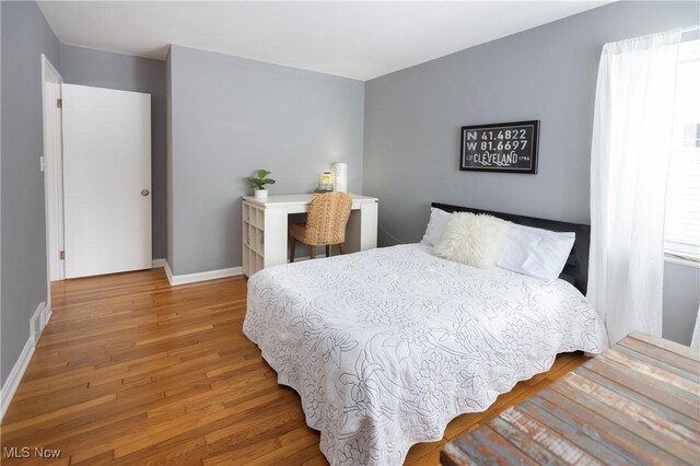 bedroom with visible vents, multiple windows, baseboards, and wood finished floors