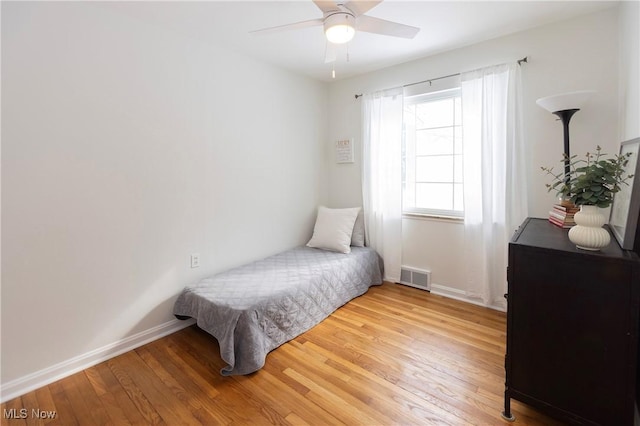 bedroom with baseboards, ceiling fan, visible vents, and light wood-style floors