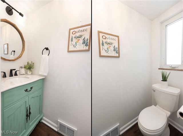 half bathroom featuring baseboards, visible vents, vanity, and toilet