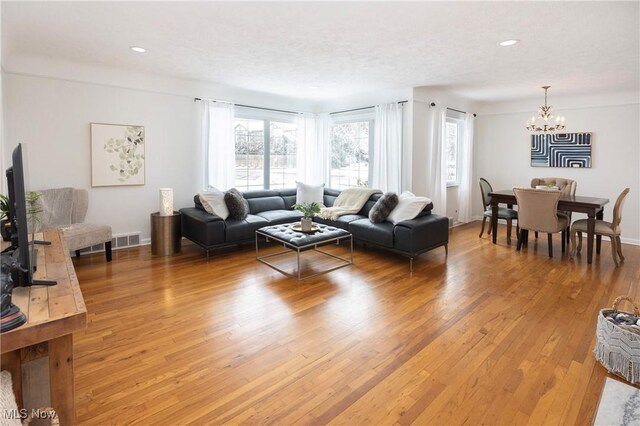 living room featuring baseboards, visible vents, wood finished floors, an inviting chandelier, and recessed lighting