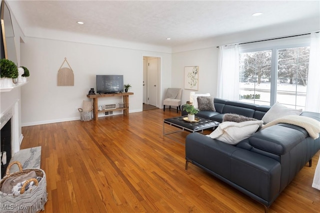 living area with a premium fireplace, baseboards, wood finished floors, and recessed lighting