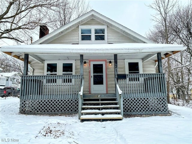 bungalow-style house featuring a chimney and a porch