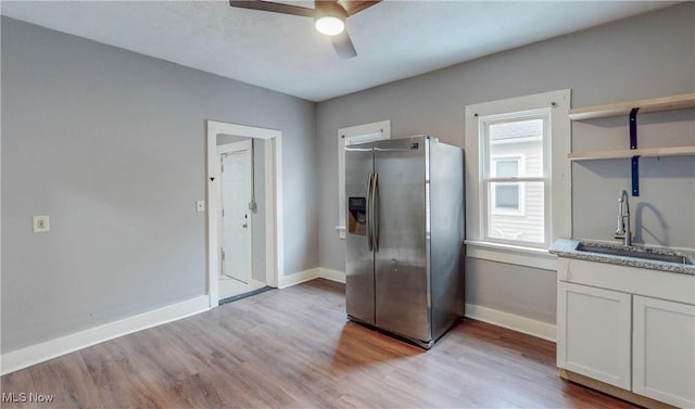 kitchen featuring open shelves, light countertops, white cabinetry, a sink, and stainless steel fridge