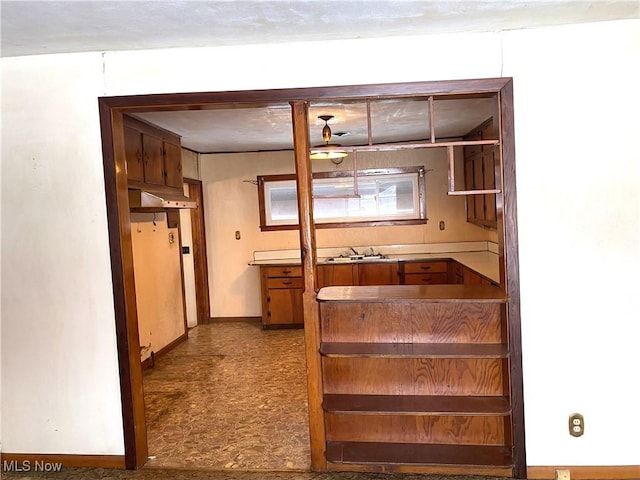 kitchen featuring light floors, baseboards, and a sink