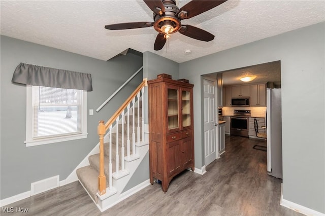 staircase with baseboards, a textured ceiling, visible vents, and wood finished floors