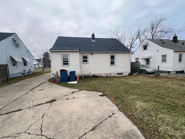 back of house featuring a yard and roof with shingles