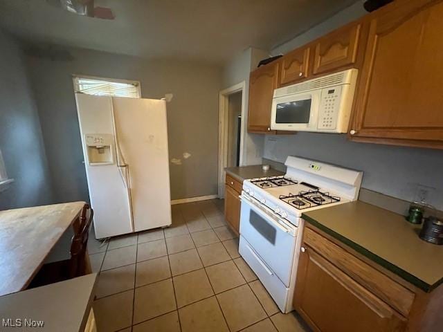 kitchen featuring white appliances, light tile patterned floors, baseboards, and brown cabinetry