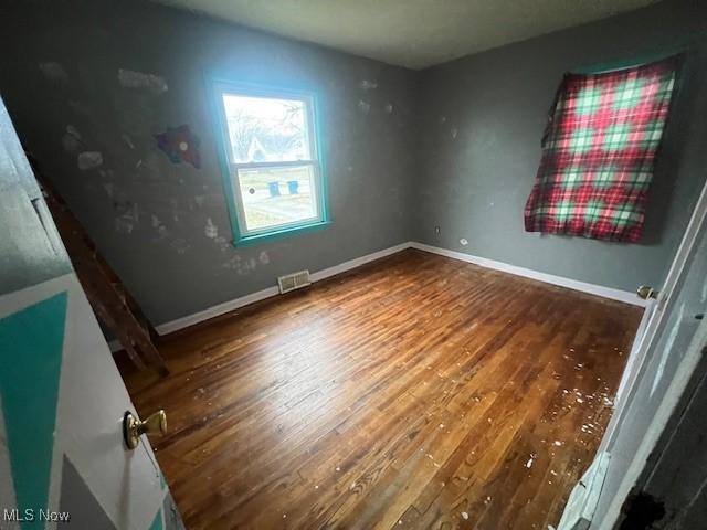 unfurnished bedroom with visible vents, baseboards, and wood finished floors