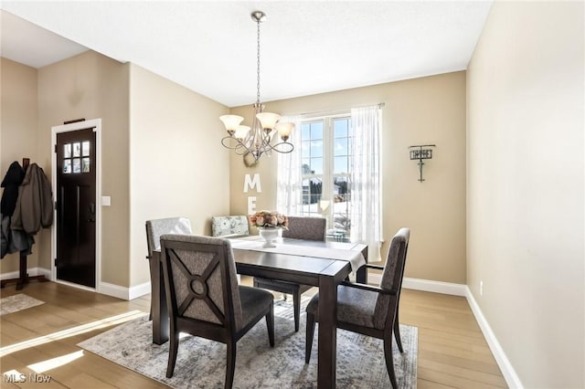 dining area featuring a healthy amount of sunlight, a notable chandelier, baseboards, and wood finished floors