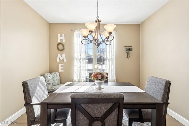 dining area with light wood-type flooring, baseboards, and an inviting chandelier