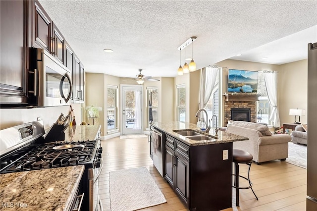 kitchen featuring a sink, open floor plan, light wood-type flooring, a kitchen bar, and stainless steel appliances