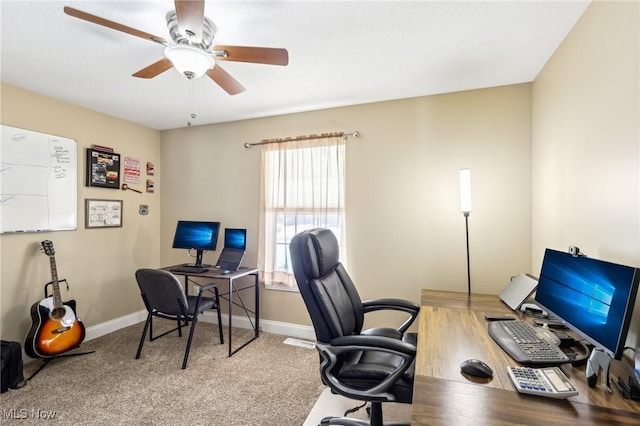 carpeted office space featuring ceiling fan and baseboards