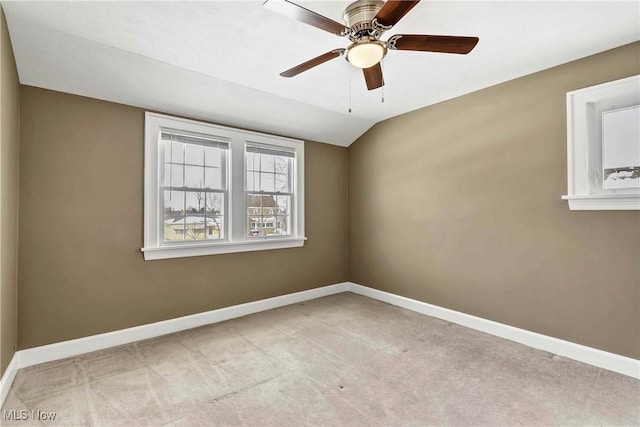 spare room featuring light carpet, ceiling fan, lofted ceiling, and baseboards