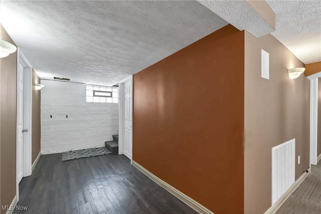 basement with visible vents, dark wood finished floors, a textured ceiling, and baseboards