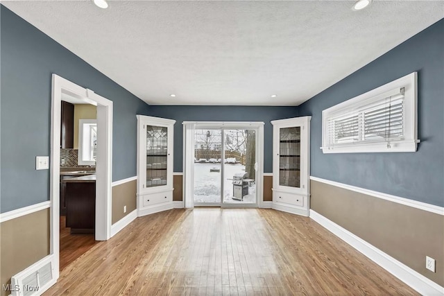 entryway featuring a textured ceiling, light wood finished floors, visible vents, and baseboards