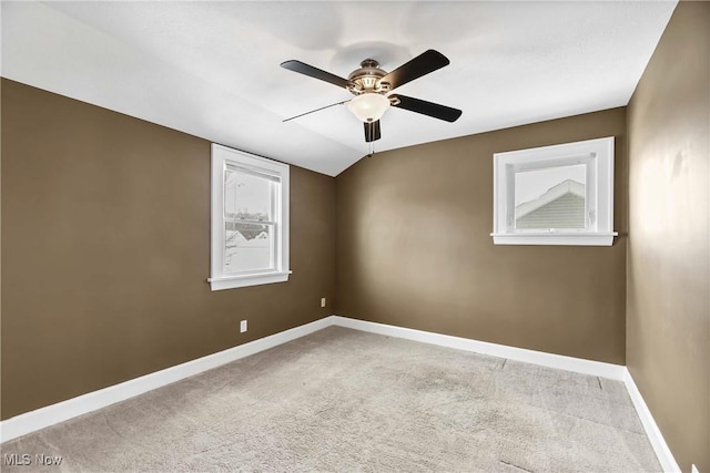 carpeted empty room featuring vaulted ceiling, baseboards, and ceiling fan