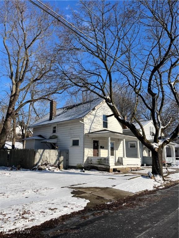 view of front of house with a porch, fence, and a chimney