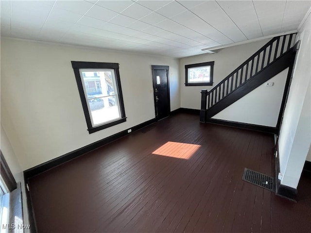 entryway with stairs, dark wood finished floors, visible vents, and baseboards