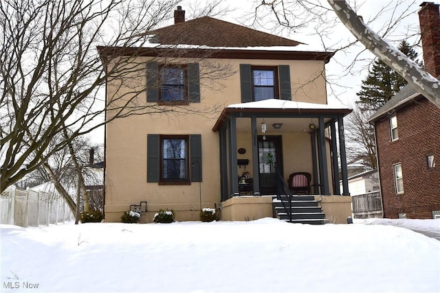 american foursquare style home with a chimney and stucco siding