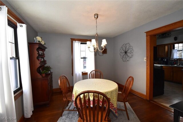 dining space with baseboards, dark wood finished floors, and a notable chandelier