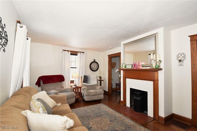 living room featuring dark wood-type flooring, a fireplace, and baseboards