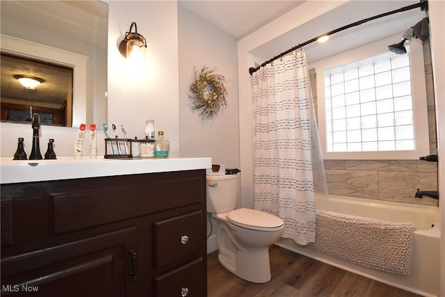 bathroom with toilet, wood finished floors, shower / bath combo with shower curtain, and vanity