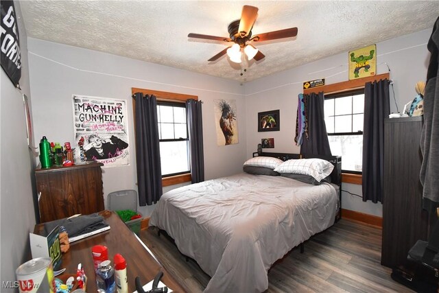 bedroom with ceiling fan, baseboards, dark wood finished floors, and a textured ceiling