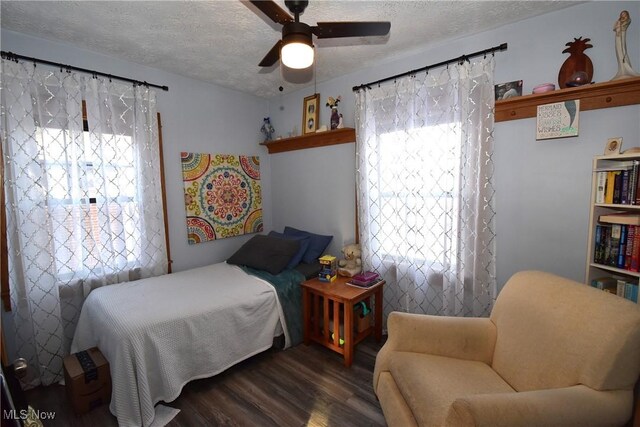 bedroom with a textured ceiling, ceiling fan, and dark wood finished floors