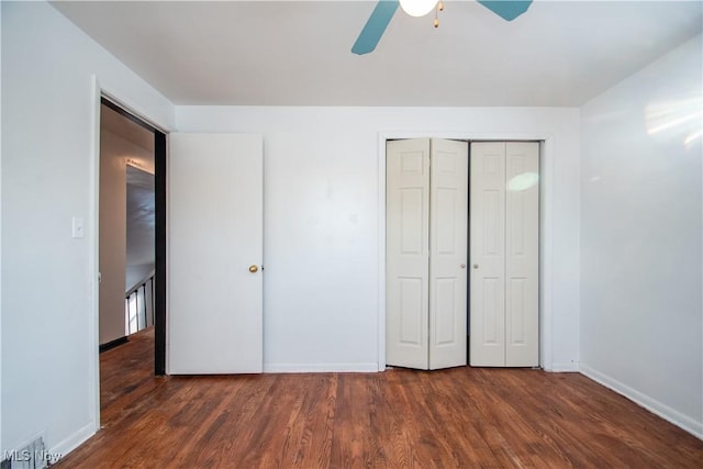 unfurnished bedroom featuring dark wood-type flooring, a closet, visible vents, and baseboards